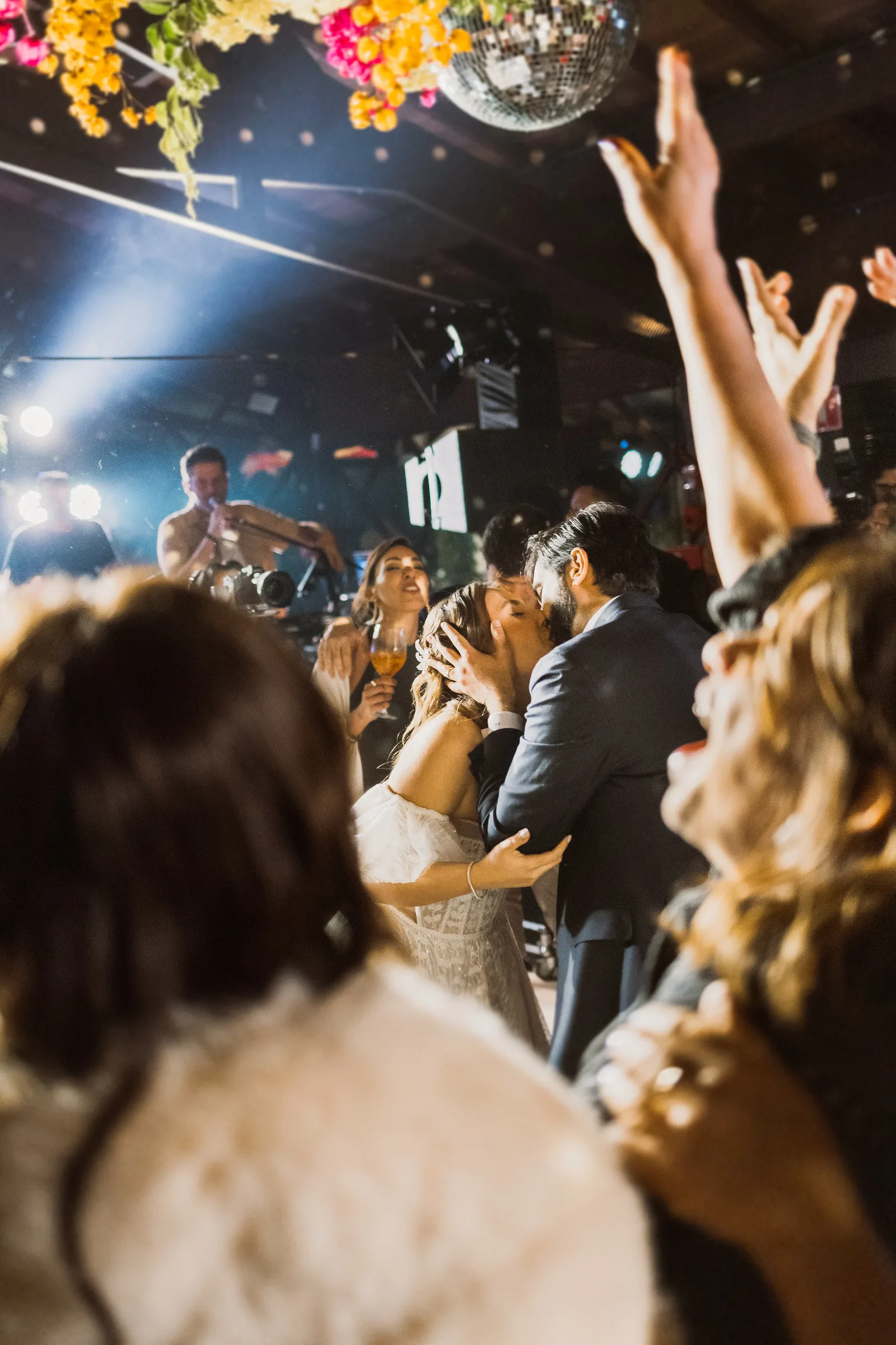 Convidados com os braços para cima na pista de dança, durante a festa de casamento