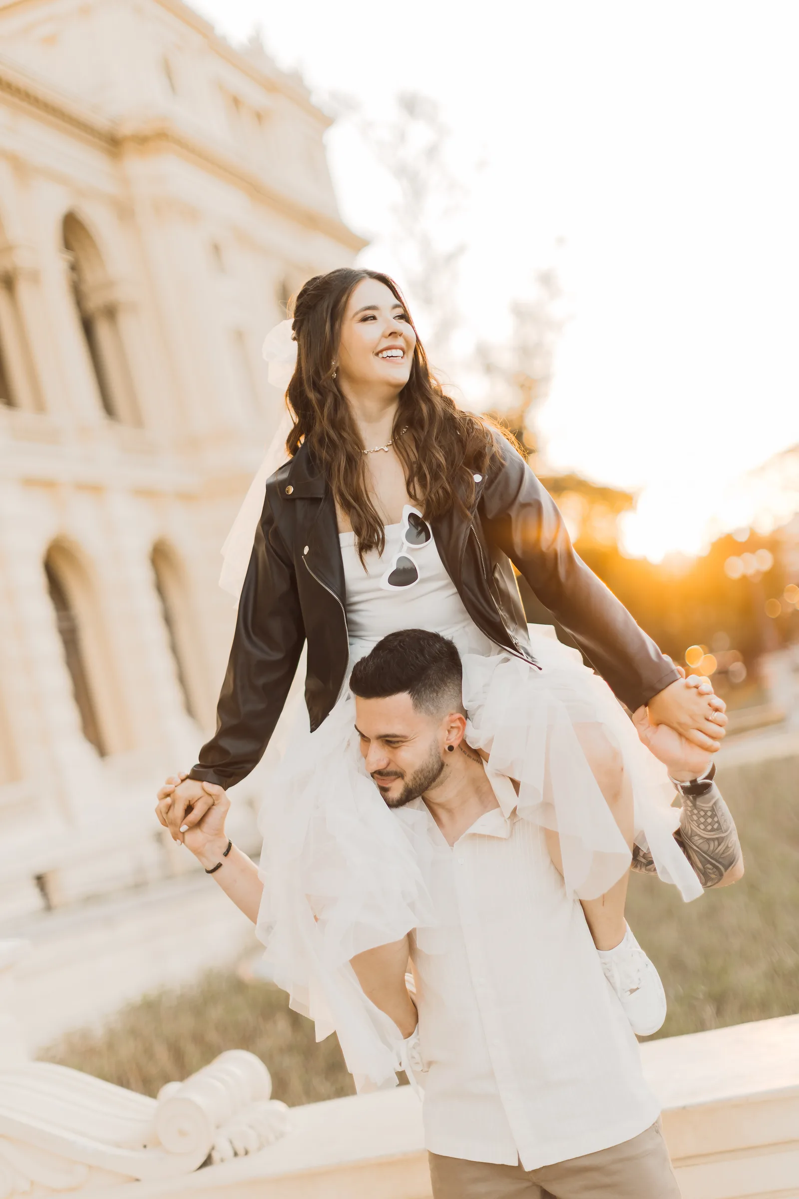 Casal rindo, ela nas costas dele, no ensaio pré-wedding no Museu do Ipiranga, em São Paulo