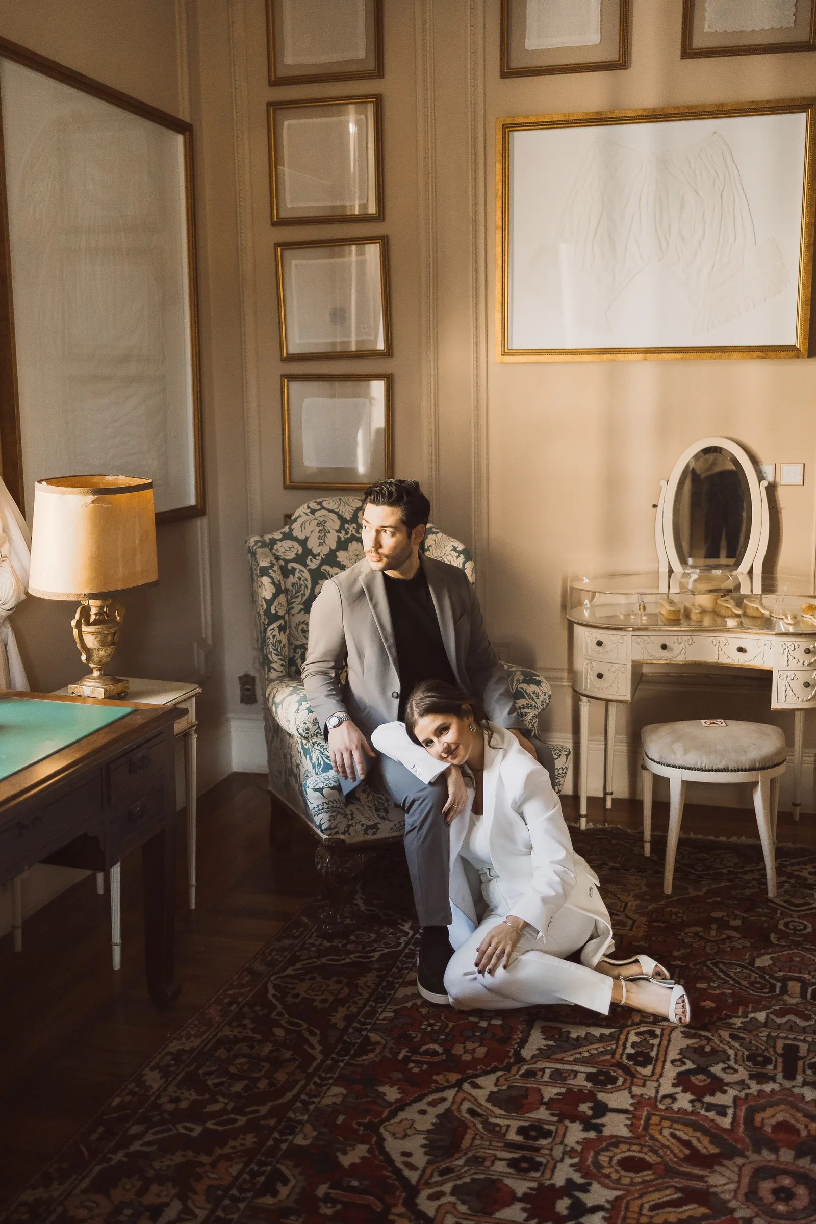 Casal em uma sala com quadros e penteadeira antiga, na Casa da Don’Anna, em São Paulo